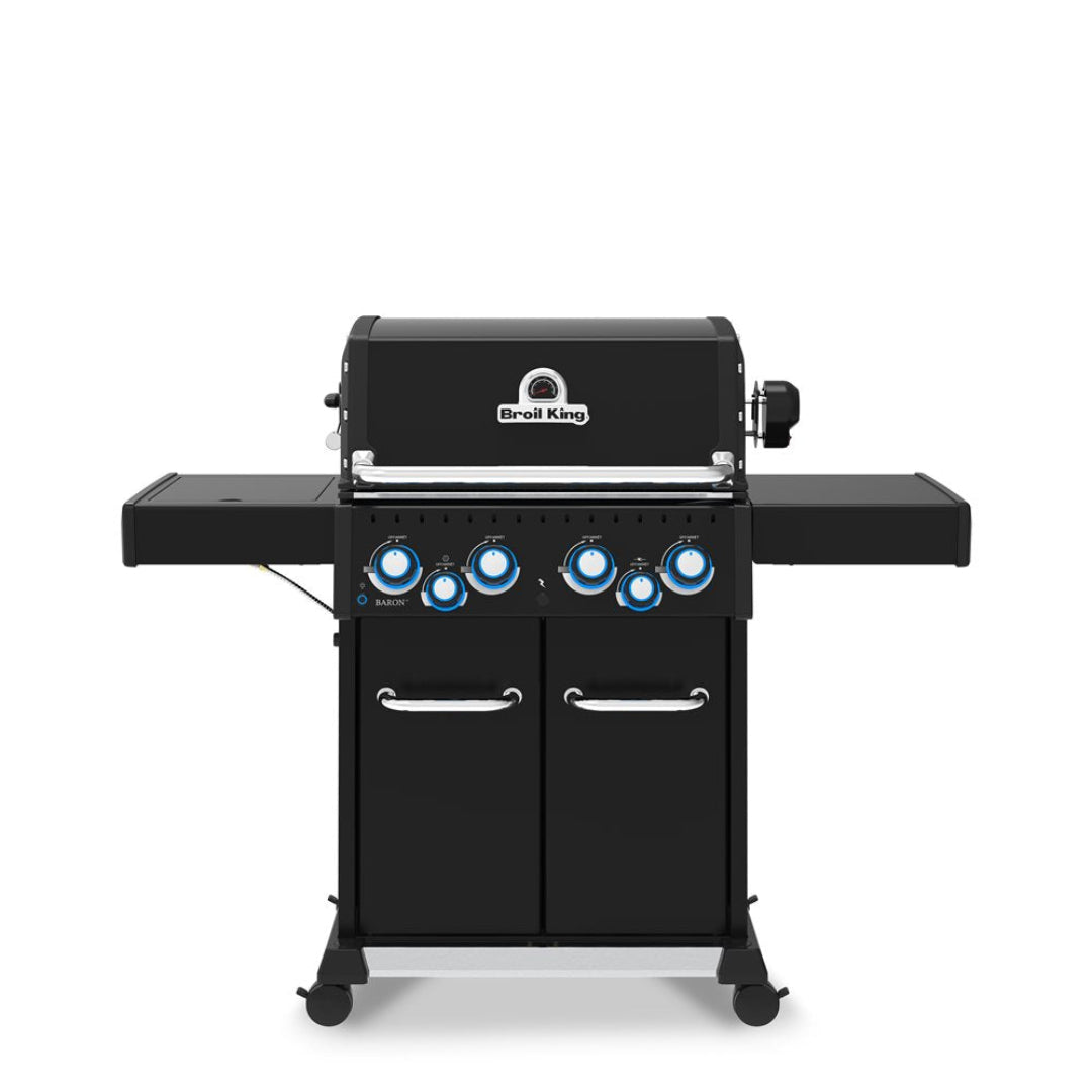 Freestanding gas grill, Broil King Baron series, 5-burner grill with side shelves, closed lid, control knobs illuminated