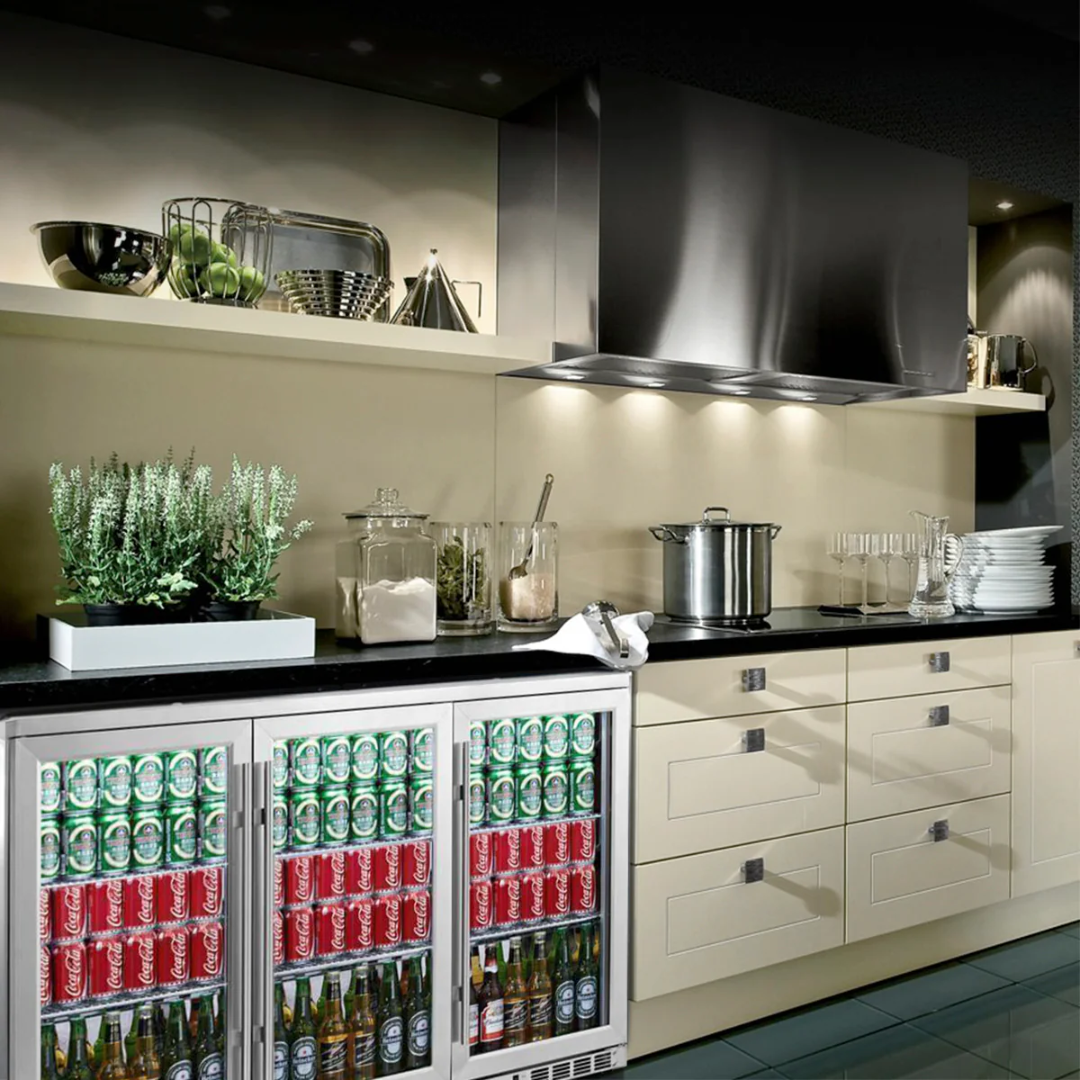 Built-in undercounter 3-door glass-door beverage refrigerator KBU328M with stainless steel trim, stocked with soda cans and beer bottles for home bar and kitchen