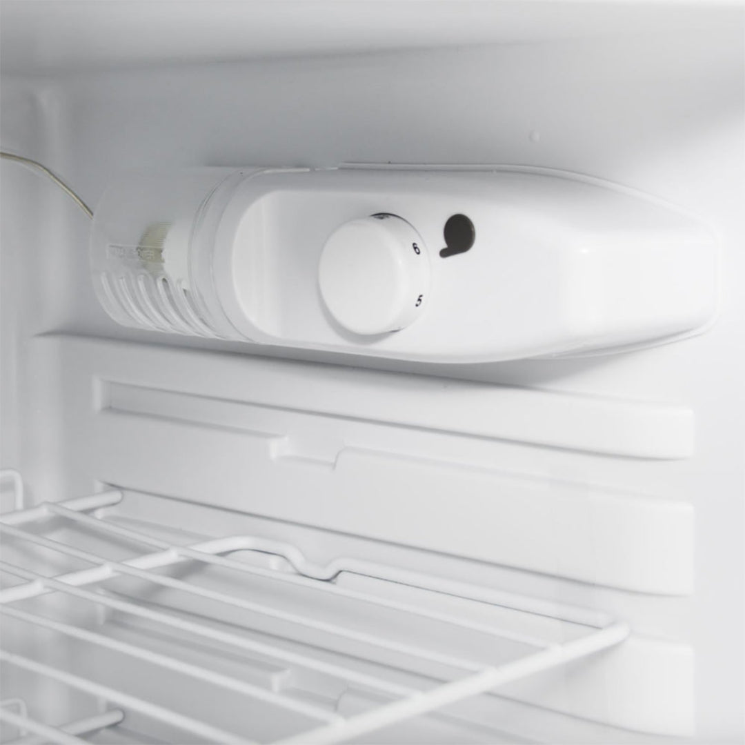 White mini fridge interior with temperature control dial set at 5–6, plastic thermostat housing and white wire shelf, compact refrigerator thermostat knob replacement