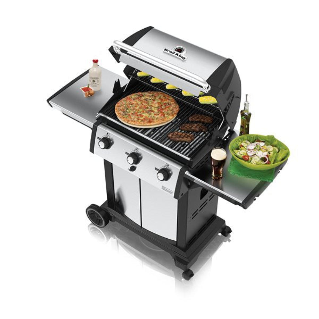 Grill in use, Broil King Signet series, open lid, pizza and steaks cooking, salad and drink on side shelf, white background